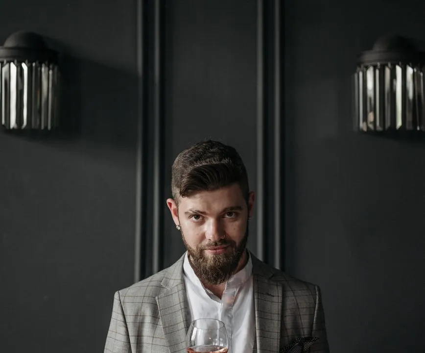 man in gray suit jacket holding a wine glass
