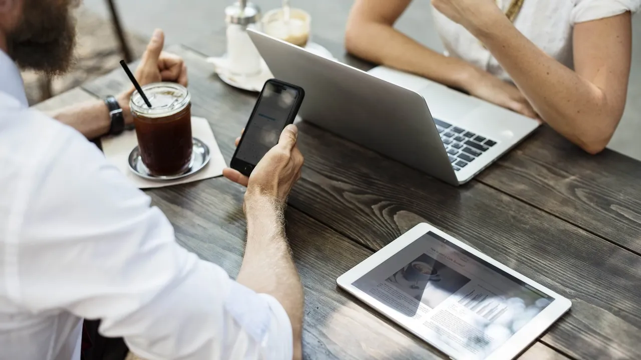 Woman using laptop next to man holding coffee